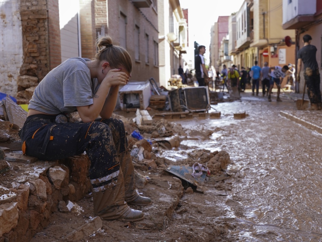 Una mujer descansa mientras residentes y voluntarios limpian una zona arrasada por las inundaciones en Paiporta, cerca de Valencia, España, el 1 de noviembre de 2024. (AP Foto/Alberto Saiz)