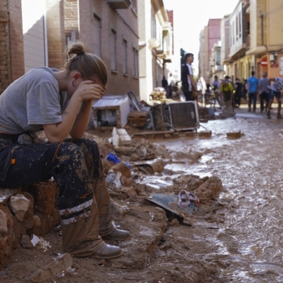 Una mujer descansa mientras residentes y voluntarios limpian una zona arrasada por las inundaciones en Paiporta, cerca de Valencia, España, el 1 de noviembre de 2024. (AP Foto/Alberto Saiz)