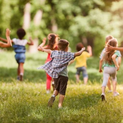 Back view of carefree kids having fun while running in springtime.