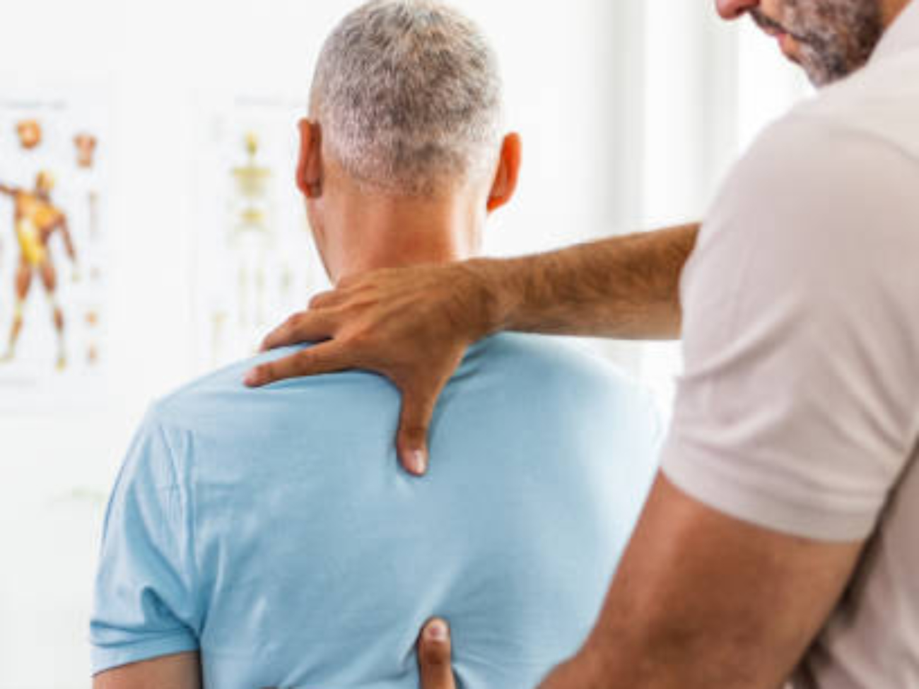 Male Doctor and patient suffering from back pain during medical exam