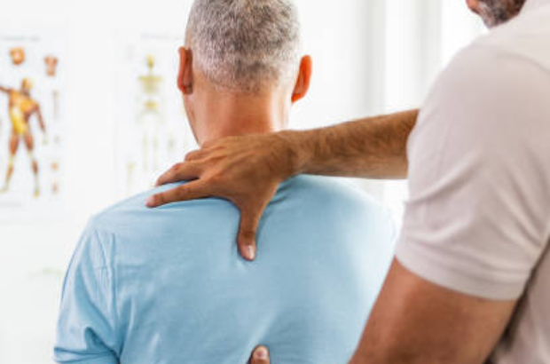 Male Doctor and patient suffering from back pain during medical exam