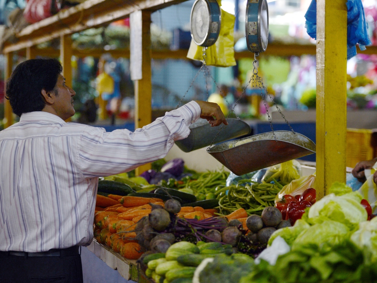 A man weighs vegetables at a popular market in Caracas on October 24, 2013. Venezuela, which is highly dependent on basic commodity imports, will massively boost its food and basic supplies imports in the next two months to counter shortages and high inflation, Vice president for the economy Rafael Ramirez said Wednesday. Since President Nicolas Maduro took office on April 19, Venezuela has seen a cyclical increase in shortages of sugar, coffee, oil, milk and toilet paper, among other products. Meanwhile, annual inflation in September soared to 49.4 percent, the highest in the past 13 years, according to official data.
 AFP PHOTO / JUAN BARRETO (Photo by JUAN BARRETO / AFP)