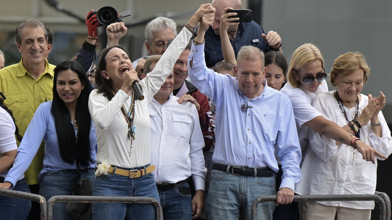 Venezuelan opposition leader Maria Corina Machado (L) talks to supporters as she rises the hand of opposition presidential candidate Edmundo Gonzalez Urrutia during a rally in front of the United Nations headquarters in Caracas on July 30, 2024. Venezuela braced for new demonstrations on July 30, after four people died and dozens were injured when the authorities broke up protests against President Nicolas Maduro's claim of victory in the country's hotly disputed weekend election. (Photo by Yuri CORTEZ / AFP)