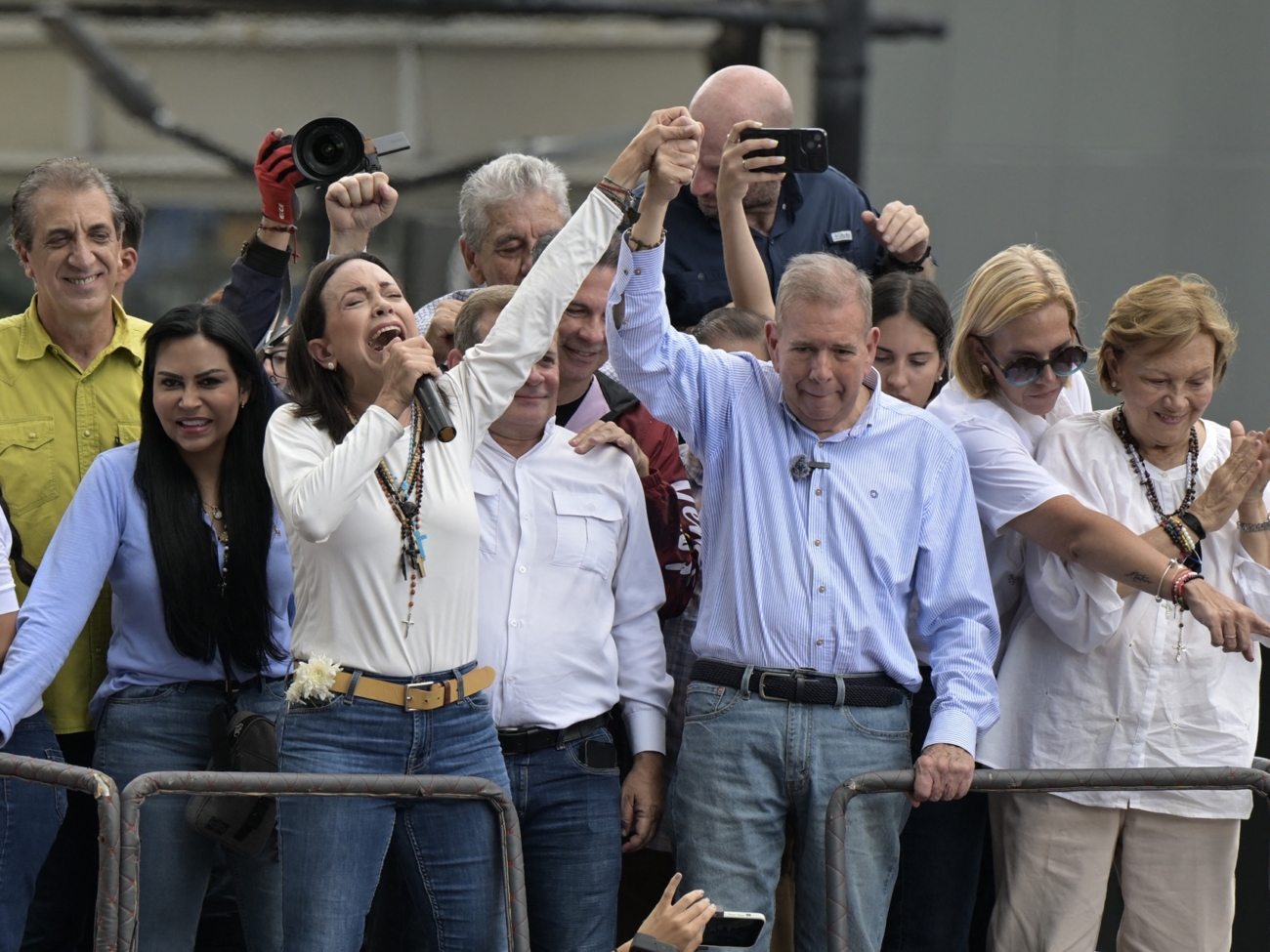 Venezuelan opposition leader Maria Corina Machado (L) talks to supporters as she rises the hand of opposition presidential candidate Edmundo Gonzalez Urrutia during a rally in front of the United Nations headquarters in Caracas on July 30, 2024. Venezuela braced for new demonstrations on July 30, after four people died and dozens were injured when the authorities broke up protests against President Nicolas Maduro's claim of victory in the country's hotly disputed weekend election. (Photo by Yuri CORTEZ / AFP)