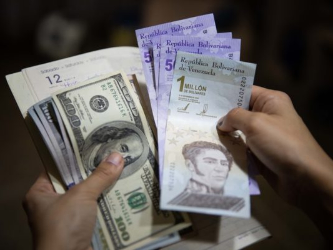 AME9701. CARACAS (VENEZUELA), 02/07/2021.- Una persona sostiene un fajo de billetes de dolar y bolívares el 01 de julio de 2021, en Caracas (Venezuela). Venezuela lleva inmersa en la pesadilla de la hiperinflación desde noviembre de 2017, una época de cifras mareantes que ha derivado en una dolarización espontánea como boya de salvación. Sin embargo, en los últimos meses, el incremento de los precios ha comenzado a frenarse, lo que alimenta la esperanza de dejar atrás el mal sueño. EFE/ Rayner Peña R