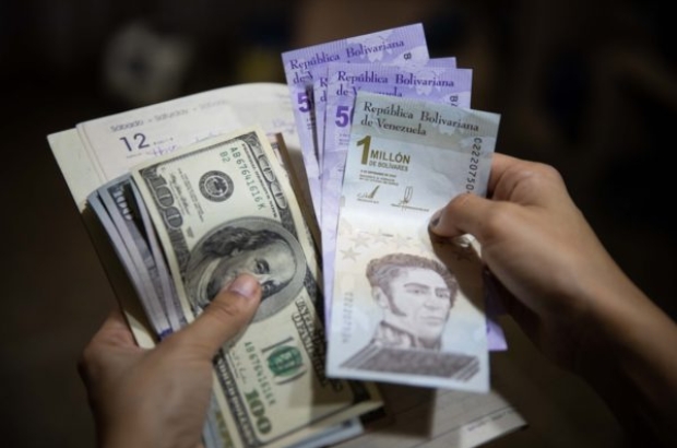 AME9701. CARACAS (VENEZUELA), 02/07/2021.- Una persona sostiene un fajo de billetes de dolar y bolívares el 01 de julio de 2021, en Caracas (Venezuela). Venezuela lleva inmersa en la pesadilla de la hiperinflación desde noviembre de 2017, una época de cifras mareantes que ha derivado en una dolarización espontánea como boya de salvación. Sin embargo, en los últimos meses, el incremento de los precios ha comenzado a frenarse, lo que alimenta la esperanza de dejar atrás el mal sueño. EFE/ Rayner Peña R